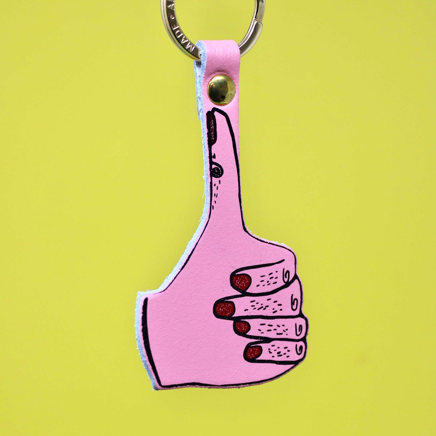 Genuine leather key ring featuring a pink hand with foil embossed nails making a thumbs up sign. In a David Shrigley style.